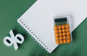 Calculadora con símbolo de porcentaje y cuaderno para calcular deducciones en la declaración de la renta en Andalucía